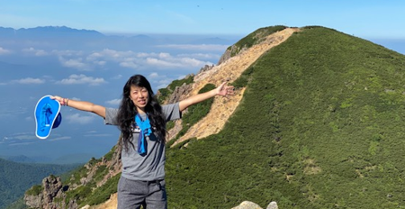 Rina celebrates at the summit after scaling a mountain.